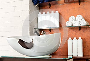 Hairdressing bowl in Beauty Salon Interior. Wash sink for washing hair, hair care spa procedures in Barber shop, shampoos, towels