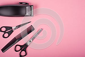 Hairdressing hair cutting tools on a pink background top view, copy space