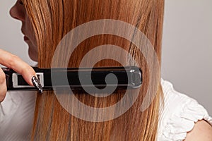 Hairdressing. Hair straightening irons and red straight hair. Healthy hair and hairstyling concept