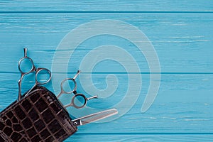 Hairdressing scissors on blue wooden background.