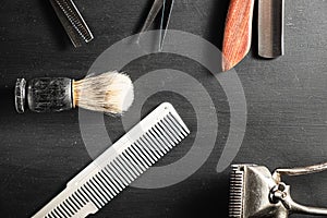 Hairdressing scissors vintage manual clipper comb brush dangerous razor are on a on a black dusty surface