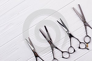 Hairdressing scissors on white wooden background.