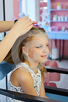 Hairdressing services. Reating hairstyle. Hair styling process. Children hairdressing salon