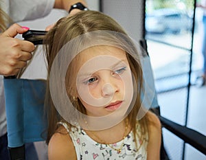 Hairdressing services. Reating hairstyle. Hair styling process. Children hairdressing salon