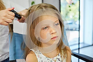 Hairdressing services. Reating hairstyle. Hair styling process. Children hairdressing salon