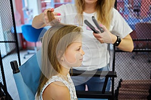 Hairdressing services. Reating hairstyle. Hair styling process. Children hairdressing salon