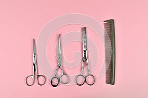 Hairdressing tools comb and different scissors on pink background