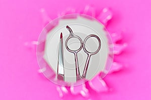 Hairdressing tools comb and scissors on torn pink paper background