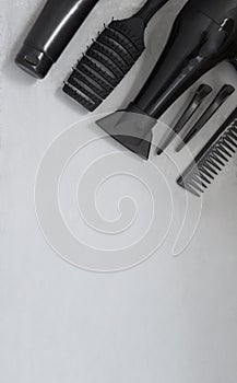 Hairdressing tools on a gray background with copy space. On the table are hair salon accessories comb, hair dryer and