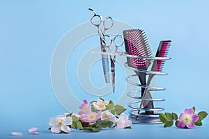 Hairdressing tools on a metal stand decorated with delicate pink flowers on a blue background photo