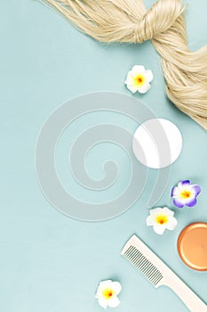 Hairdressing tools, nourishing mask and hair extensions on blue wooden background. Hair care concept flat lay