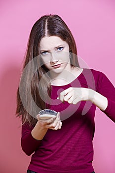 Hairloss Issues. Young Caucasian Female Having Hair Problems as Checking Hair in Hairbrush While Posing in Red Dress Against Pink