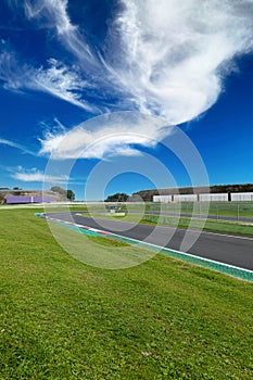 Hairpin bend and turn exit with curb and green field on motor sport circuit asphalt track