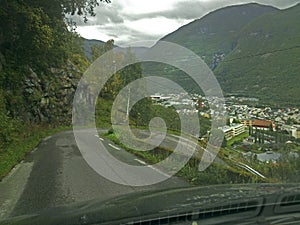 Hairpin curve on a steep road photographed from inside a car through the front window.