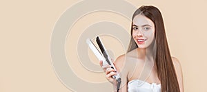 Hairstyle. Beautiful smiling woman ironing long hair with flat iron. Woman straightening hair with straightener