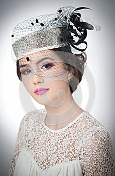 Hairstyle and make up - beautiful young girl art portrait. Cute brunette with white cap and veil, studio shot. Attractive girl