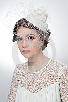 Hairstyle and make up - beautiful young girl art portrait. Cute brunette with white cap and veil, studio shot. Attractive girl