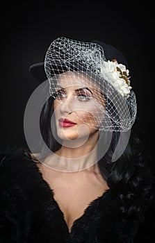 Hairstyle and make up - beautiful young woman art portrait. Cute brunette with white veil and flower arrangement, studio shot