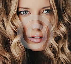 Hairstyle model and beauty face closeup. Beautiful blonde woman with long straight blond hair styled in curly waves
