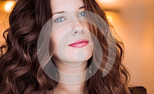 Hairstyle model and beauty face closeup. Beautiful woman with long straight brown hair styled in curly waves, classic