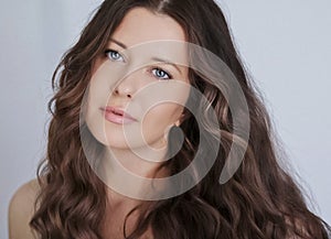 Hairstyle model and beauty face closeup. Beautiful woman with long straight brown hair styled in curly waves, classic