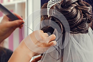 Hairstyling process. Beautiful wedding hairstyle. Hairdresser master making curls. Rear view of stylish close-up hairdress of the