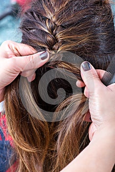 Hairstylist braiding the brown hair of a woman