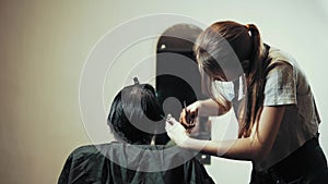 Hairstylist cut female hair during haircutting in hairdressing salon.