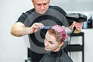 Hairstylist dries hair of woman