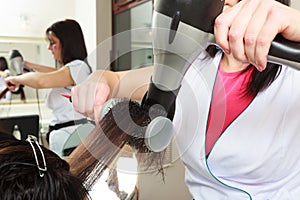 Hairstylist drying hair woman client in hairdressing beauty salon