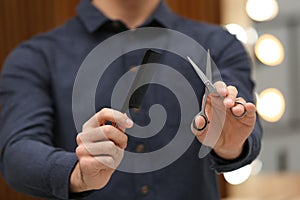 Hairstylist holding professional scissors and comb in beauty salon,