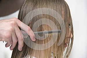 Hairstylist's Hand Combing Client's Hair In Parlor