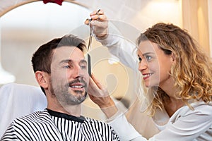 hairstylist smiling while cutting hair to handsome client