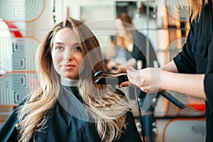 Hairstylist straightens hair, hairdressing salon