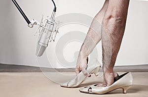 Hairy man's arms recording Foley of female footsteps on wood and in front of a silver professional studio microphone