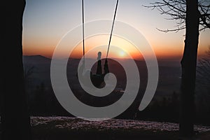 Hairy young boy aged 16-20 of European descent enjoys his life swinging on a swing at sunset on the top of Prasiva mountain in the