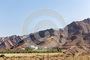 Hajar Mountains range in Hatta, with large Hollywood style Hatta sign on top of the hill, United Arab Emirates