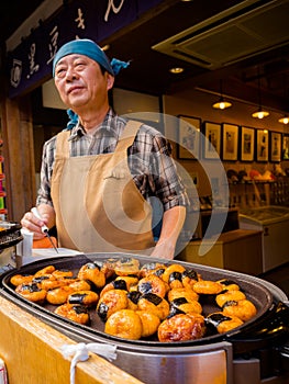 HAKONE, JAPAN - JULY 02, 2017: Unidentified Japanese man cooking food at street, based on mobile food stands where