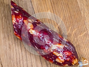 Half of an appetizing sausage on a wooden background, close-up shot. Food on a cutting board. Smoked sausage on a rustic table.