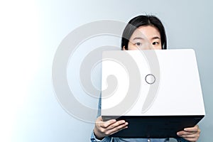 Half of Asian business woman FACE, holding laptop over BLUE sky background with copy text space, Looking at camera.