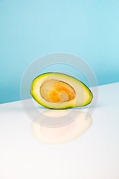 Half avocado fruit on white table.