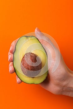 Half of avocado with kernel in female hand