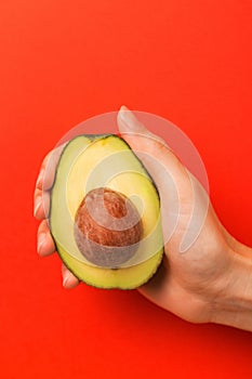 Half of avocado with kernel in female hand