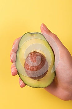 Half of avocado with kernel in female hand