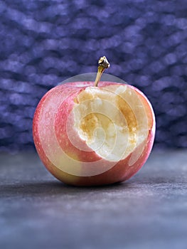 Half bitten off apple lies on gray textured background