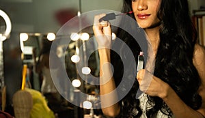 Half body disable person without fingers thumb hand of young adult woman using cosmetic brush lipstick at make up mirror desk.