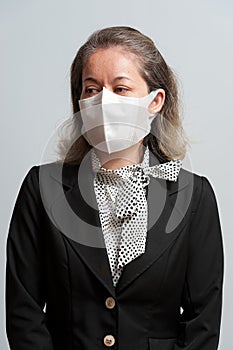 Half body portrait of middle-aged mixed race woman in formal wear wearing white disposable 3D face mask for protection against nov