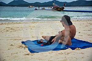 Half body shot of a handsome young man laying on a tropical beach in Thailand