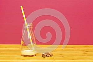 Half bottle of banana milkshake with straw and cookie crumbs