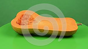 Half butternut squash Cucurbita moschata, butternut pumpkin or guitar gramma isolated on green. Side view.